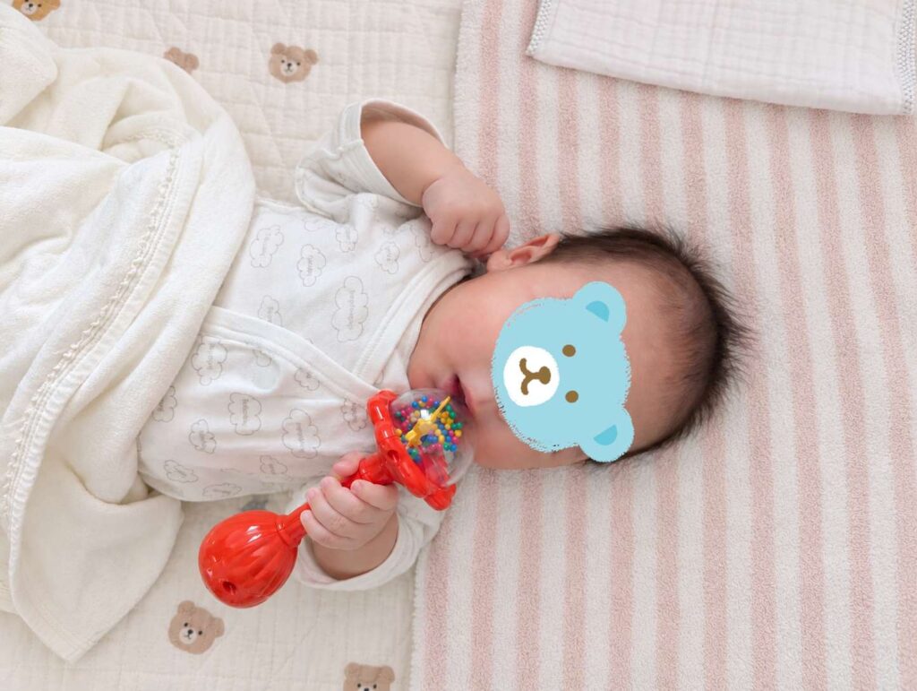 ラトルをアイスクリームのようにペロペロする0歳